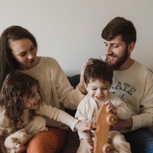 A joyful family of four sitting together on a sofa, enjoying their time with toys.